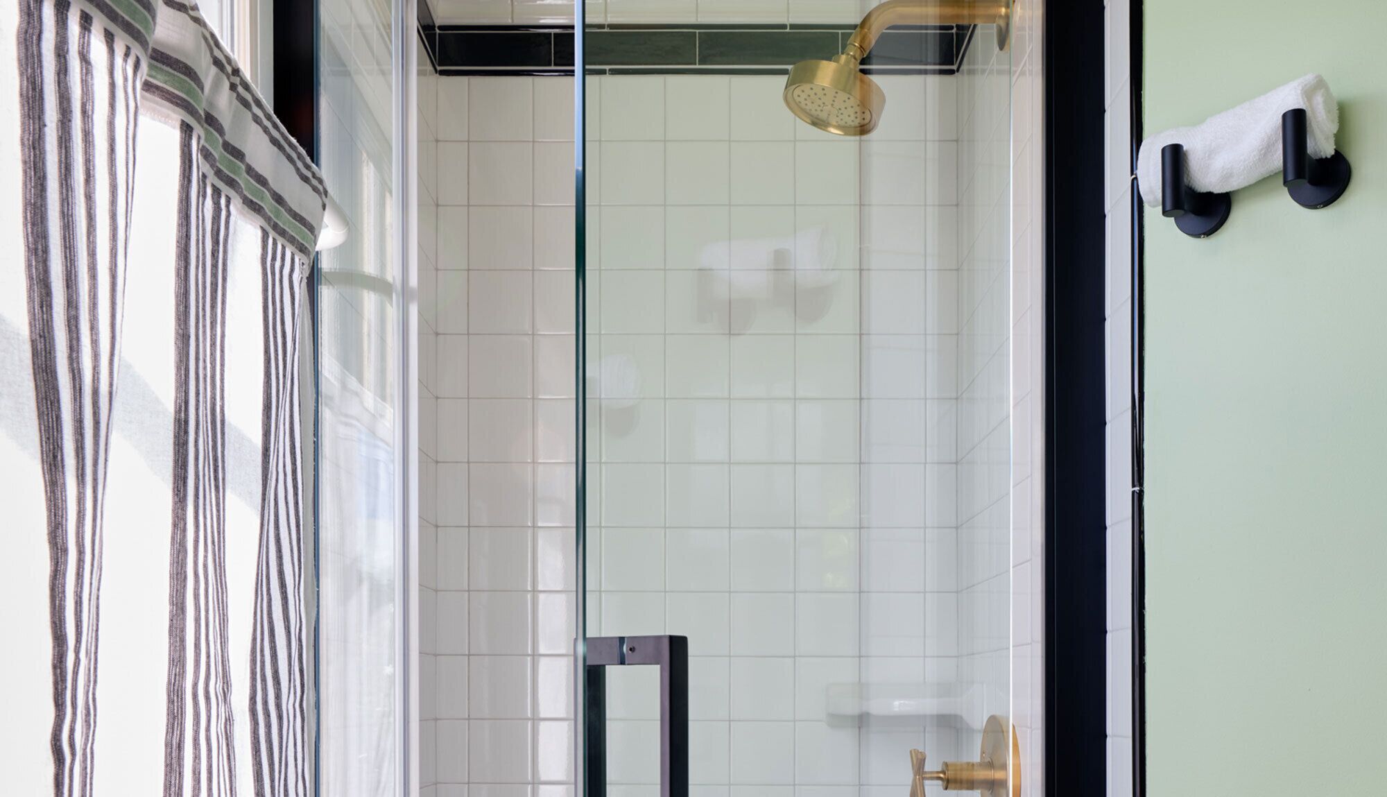 Ein modernes Badezimmer mit Duschkabine aus Glas, weißen Fliesen und einem Handtuchhalter an der Wand.