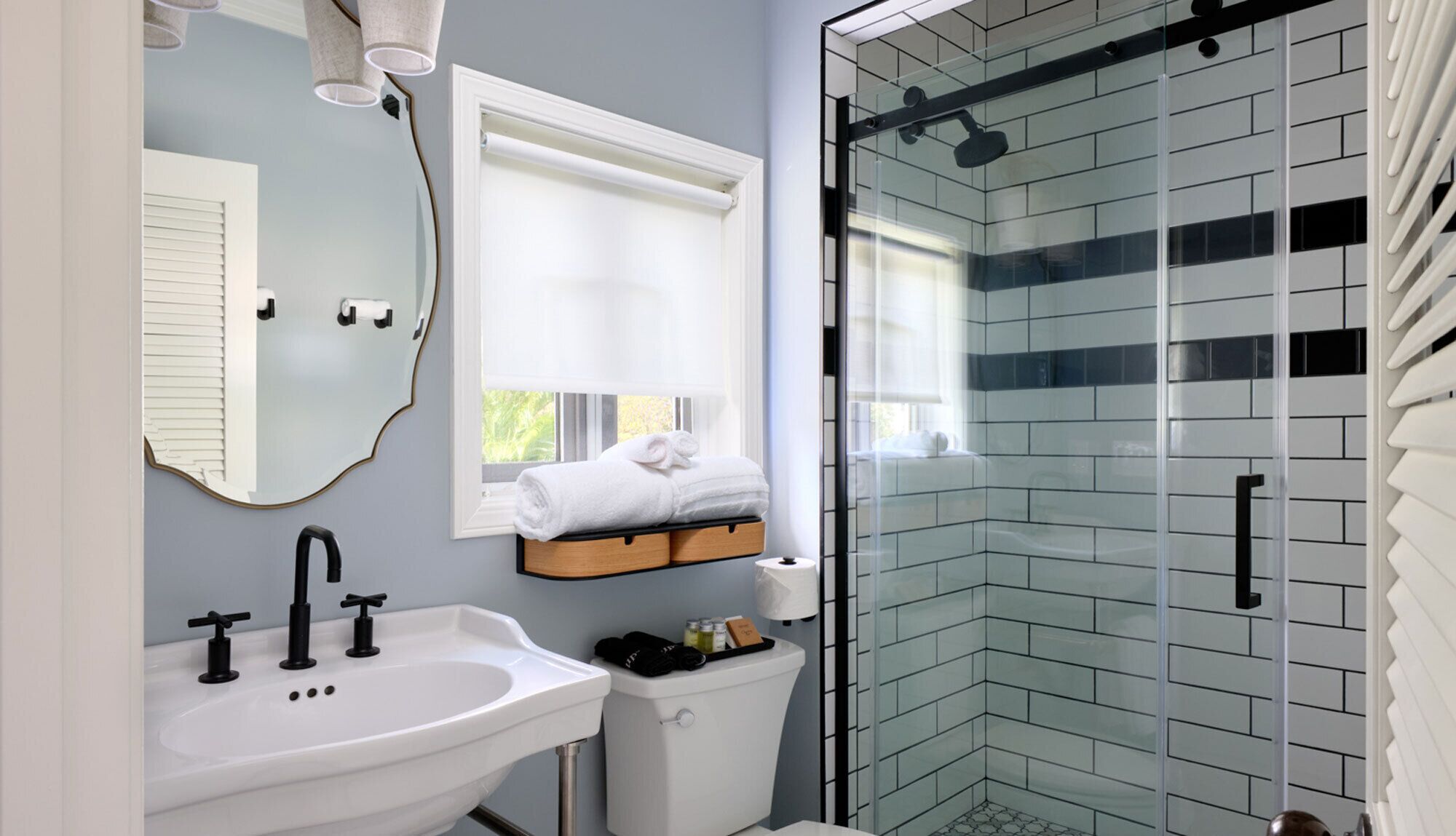 A modern bathroom with a white sink, a mirror, a toilet, and a glass shower enclosure.