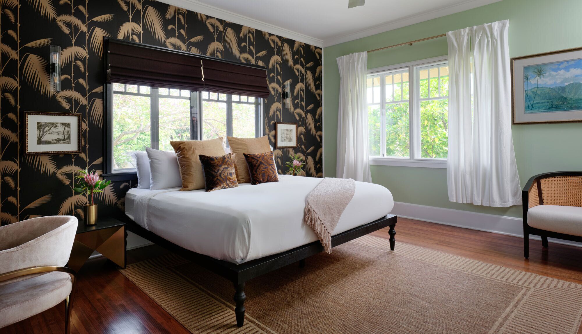 A bedroom with a bed, a nightstand, a chair, a window with curtains, and a painting on the wall.