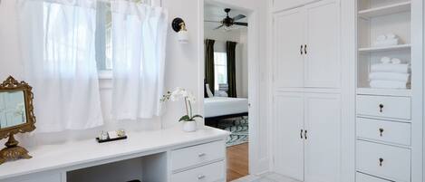 Un baño blanco con tocador, espejo y cabina de ducha.