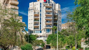 A multi-story hotel with balconies, surrounded by greenery and a clear sky. - Mascarat by Interhome (Calpe/Calp)