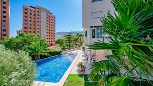 A swimming pool surrounded by greenery, with modern buildings in the background. - Mascarat by Interhome (Calpe/Calp)