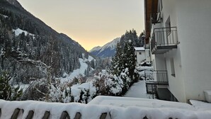 A snow-covered mountain landscape with a building featuring balconies and a view of the valley. - Sonnenseite by Interhome (Kappl)