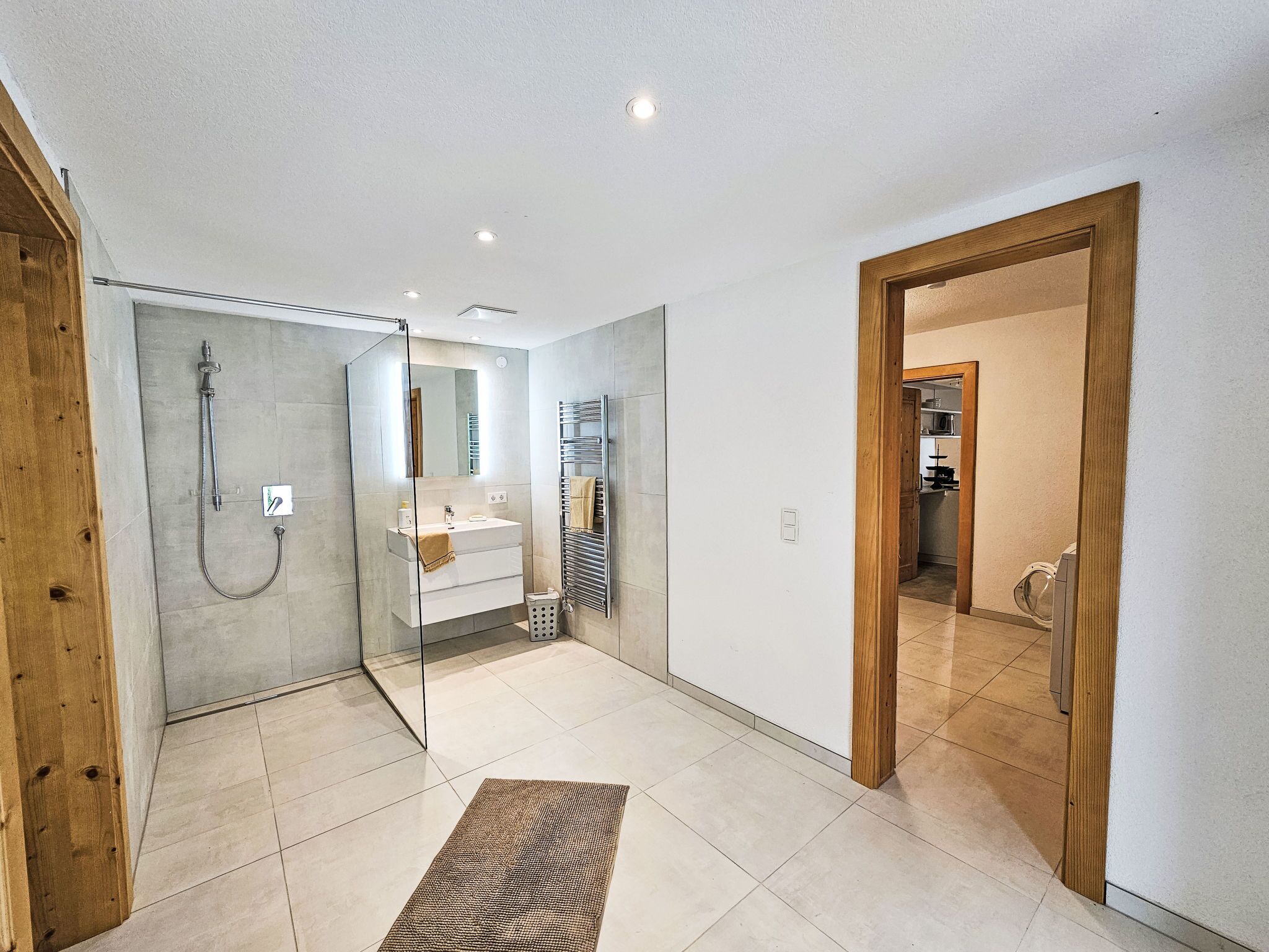 A modern bathroom with a glass shower enclosure, a white sink, and a towel rack.