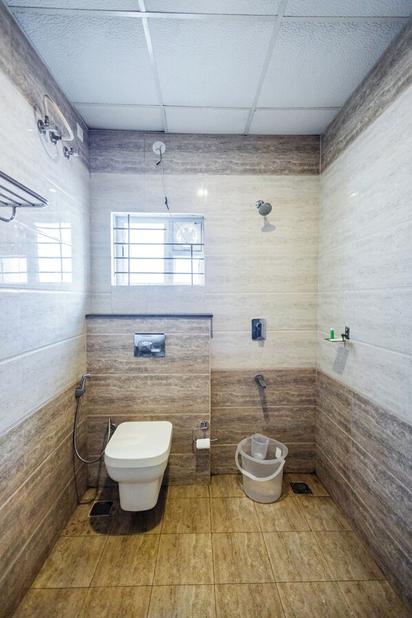 Une petite salle de bain avec des toilettes, une douche et une fenêtre.
