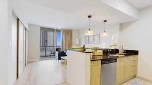 Une cuisine moderne dotée d’un îlot central, d’appareils électroménagers en acier inoxydable et de luminaires suspendus.