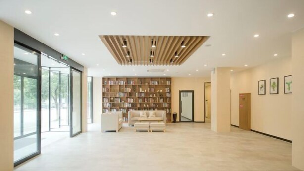 A spacious lobby with a large bookshelf, a sofa, and a reception desk.