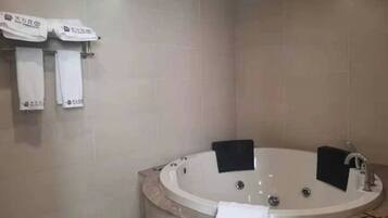 A bathroom with a freestanding bathtub, a towel rack with towels, and a shower area.