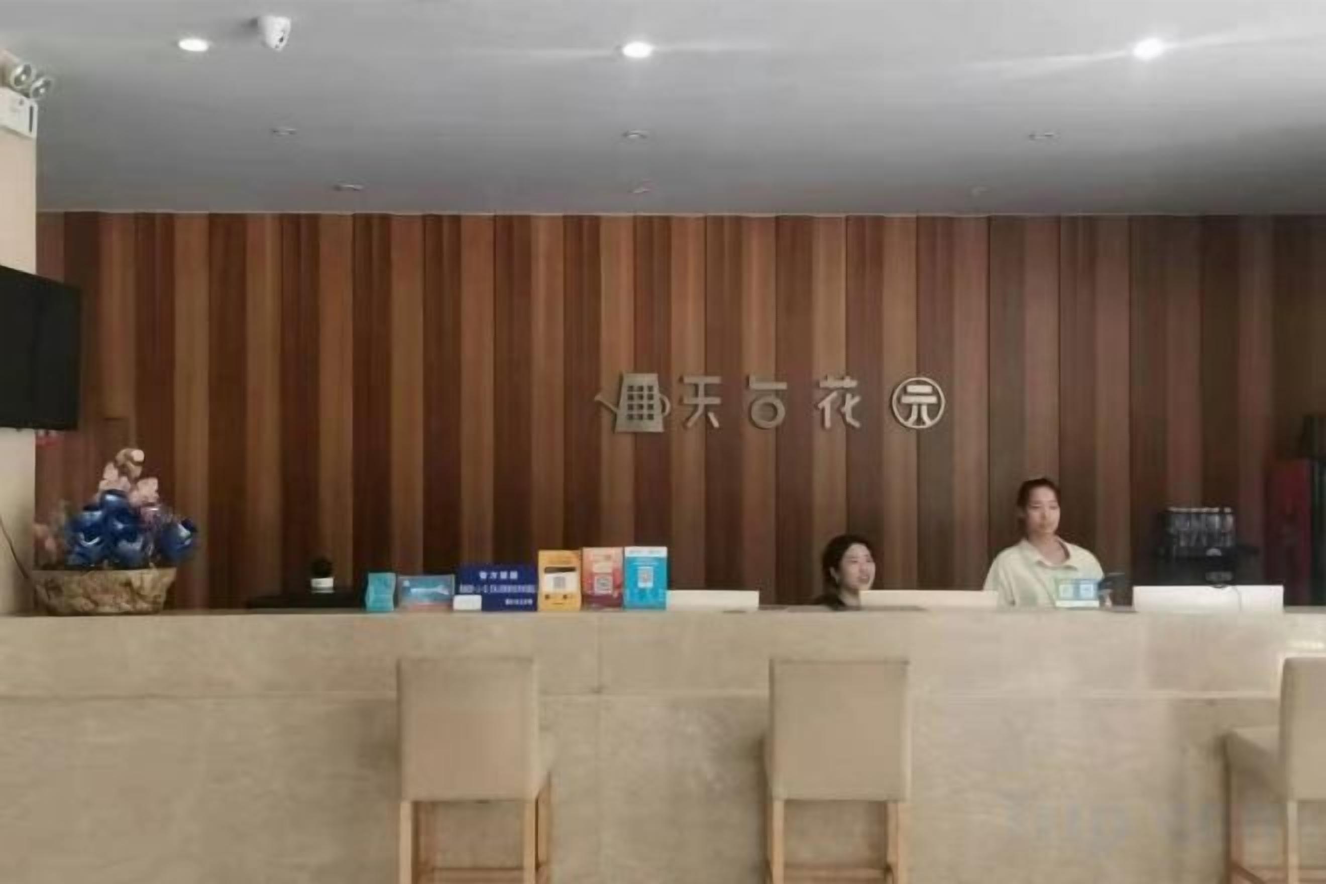 Et receptionsområde med en væg af træpaneler, en receptionsdisk og flere stole.