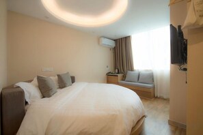 A hotel room with a large bed, a bedside table, a TV, and a window with curtains. - Tiantian Garden Boutique Hotel (Tongxiang Zhen'dong store） (Tongxiang)