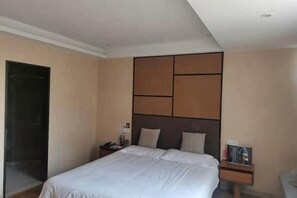 A hotel room with a large bed, a bedside table, a nightstand, and a headboard with a geometric design. - Tiantian Garden Boutique Hotel (Tongxiang Zhen'dong store） (Tongxiang)