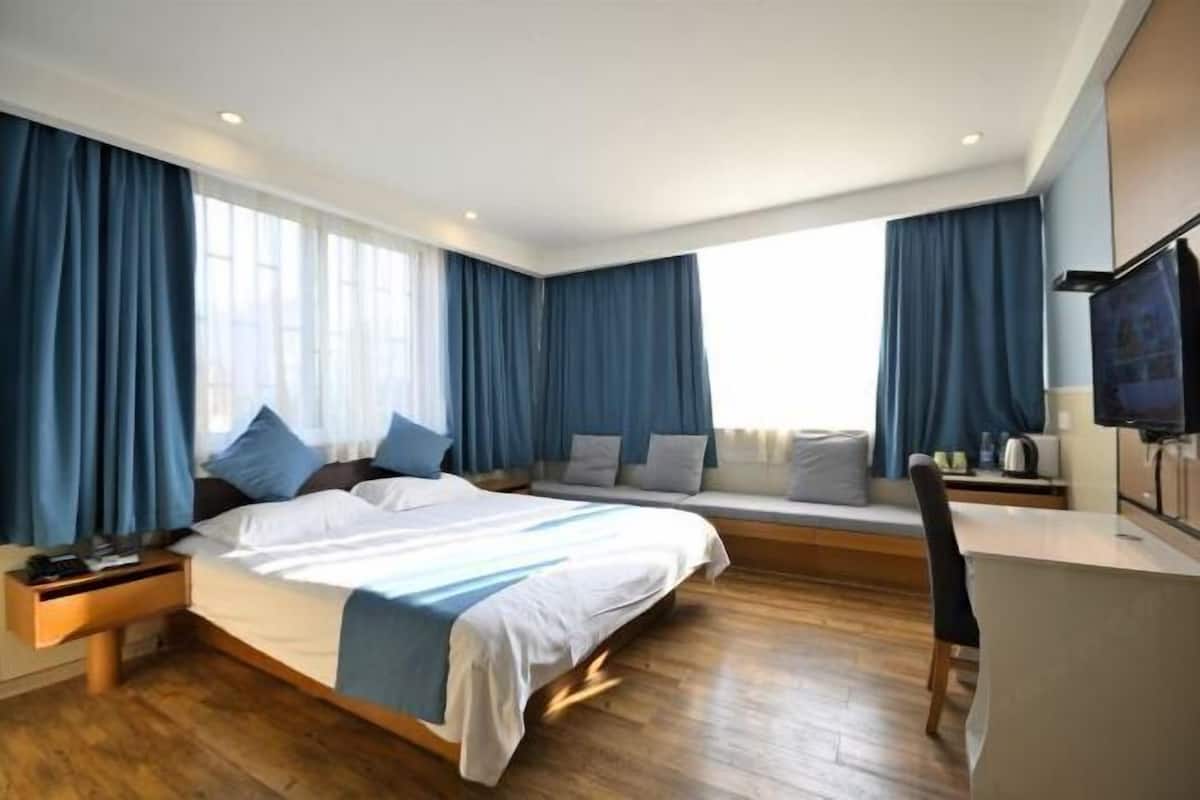 Ein modernes Hotelzimmer mit einem großen Bett, einem Schreibtisch und einem Fernseher.