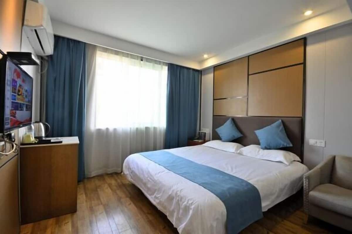 Ein Hotelzimmer mit Bett, Schreibtisch, Stuhl und Fernseher.