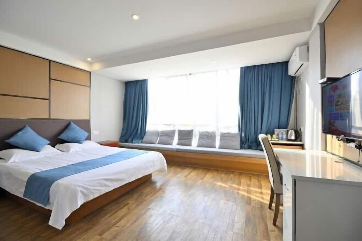 Ein modernes Hotelzimmer mit einem großen Bett, einem Schreibtisch und einem Fernseher.