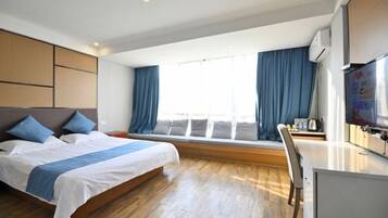 Una habitación de hotel moderna con una cama grande, un escritorio y un televisor.
