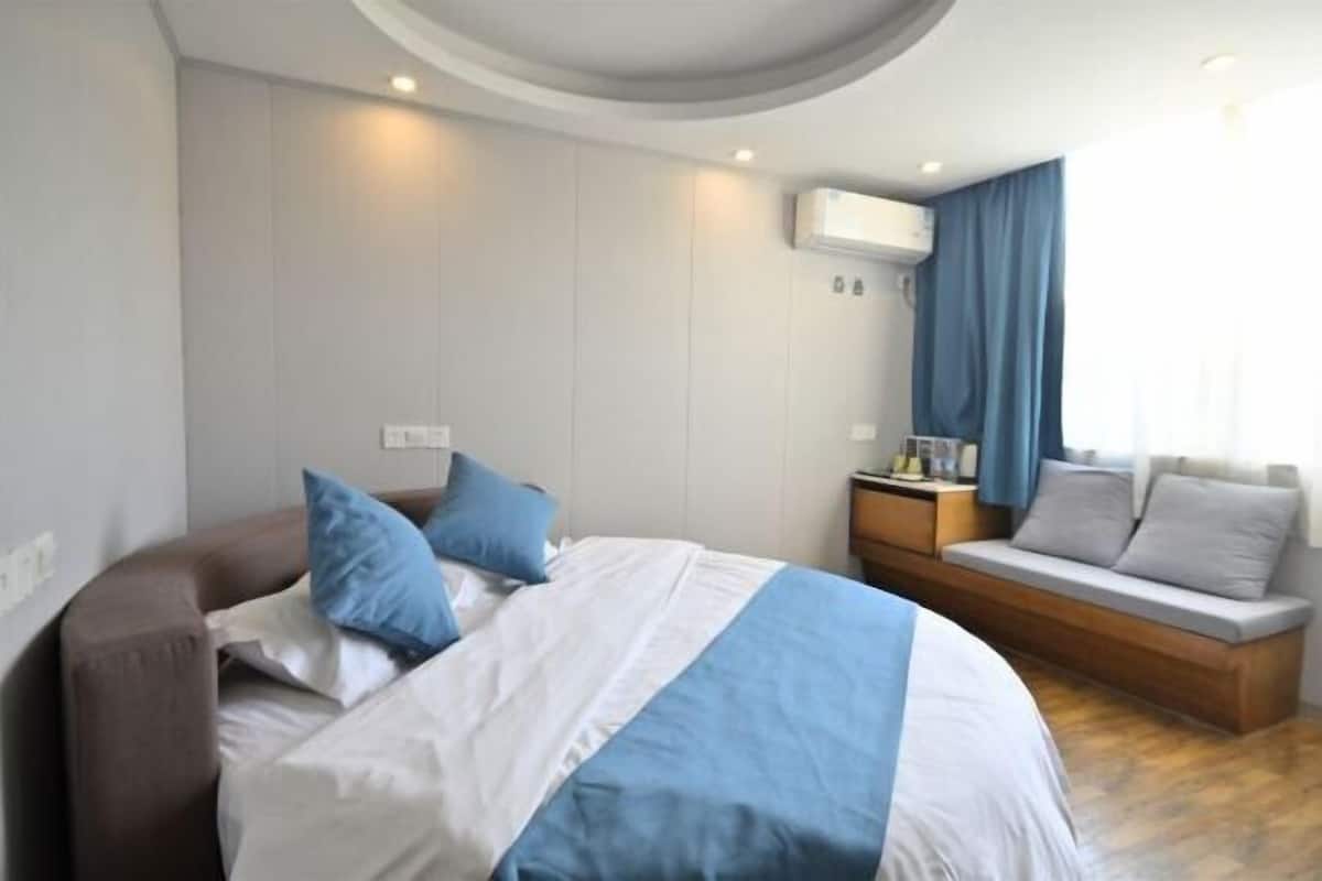 Ein modernes Hotelzimmer mit einem großen Bett, einer Couch, einem Nachttisch und einer integrierten Sitzbank.