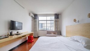 A hotel room with a bed, a TV, a wooden desk, and a window with curtains. - Nanning Boqian Business Hotel (Nanning)