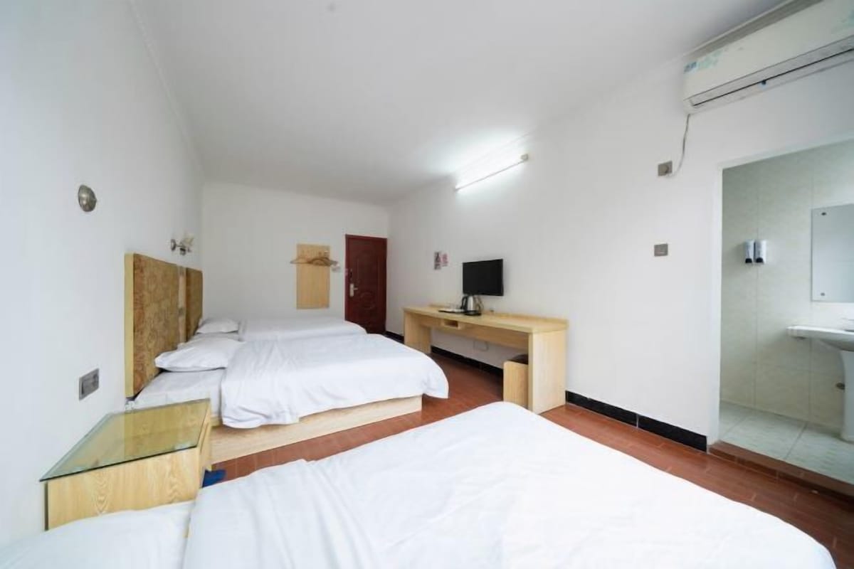 Hotelkamer met twee bedden, een houten bureau, een flatscreen televisie en een badkamer met spiegel en wastafel.