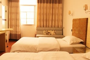Een hotelkamer met twee bedden, een bureau en een raam met gordijnen.