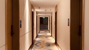 A hotel hallway with doors on both sides, a patterned carpet, and a light fixture on the ceiling.