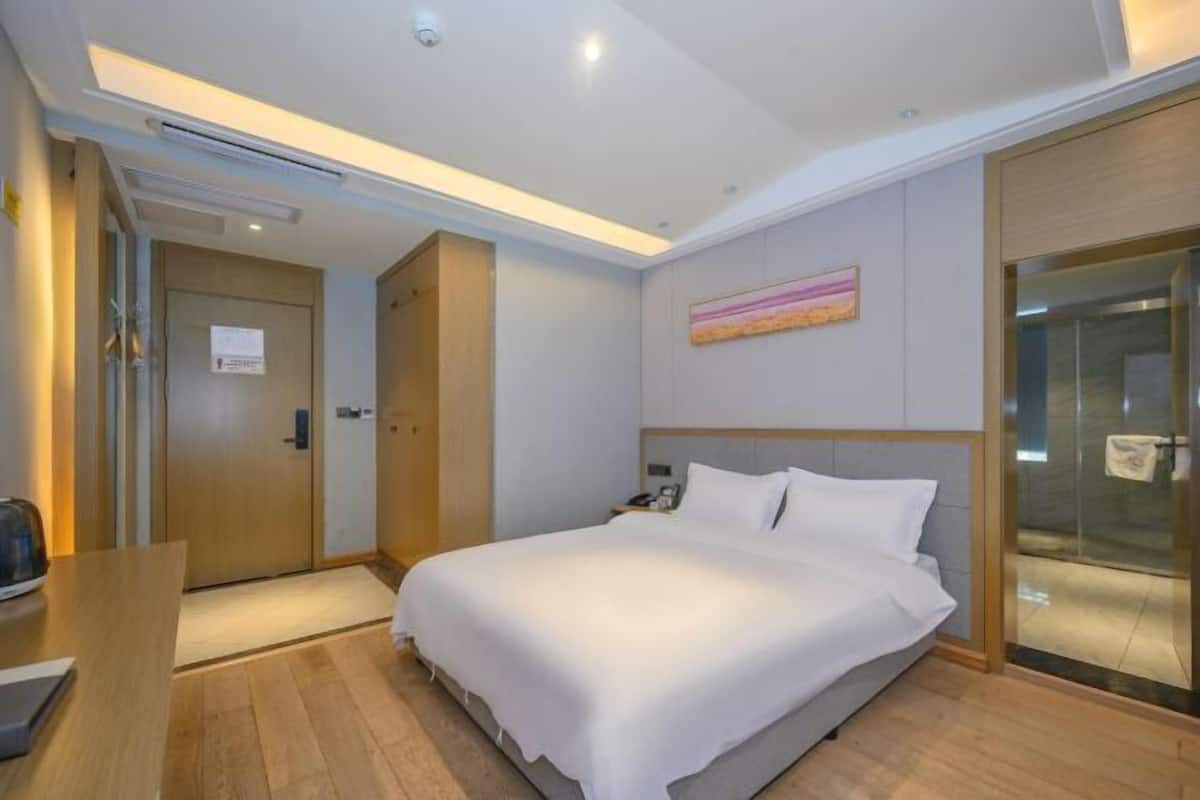 Habitación de hotel con cama, escritorio, ducha y un cuadro en la pared.