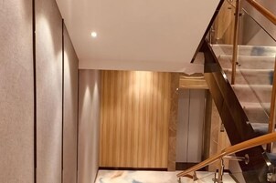 Un interior moderno con una escalera, un panel de madera y una barandilla de vidrio.