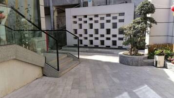 Une cour avec un escalier, un arbre en pot et la façade d’un immeuble moderne.