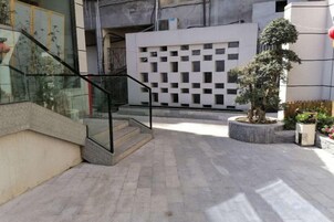Un patio con una escalera, un árbol en maceta y fachada de un edificio moderno.