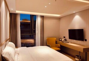 A hotel room with a bed, a desk, a chair, a TV, and a window with curtains. - Classic Hotel (Yuechi)