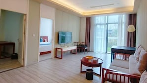 Ein Hotelzimmer mit Bett, Fernseher, Sitzgelegenheit und Blick ins Freie.