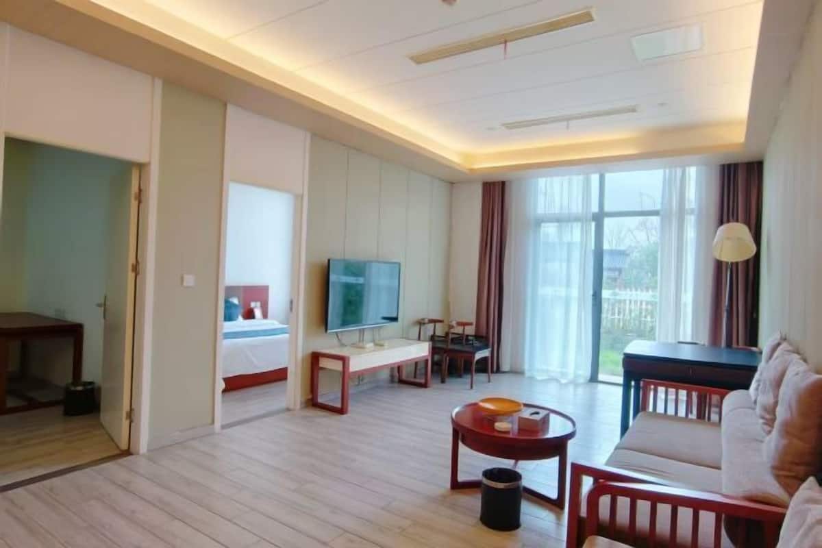 Een hotelkamer met een bed, televisie, zithoek en uitzicht op de omgeving.
