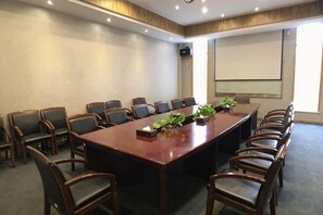 A conference room with a long table, multiple chairs, a projector screen, and a plant on the table. - Jinting Bishuiying Holiday Hotel (Suzhou)