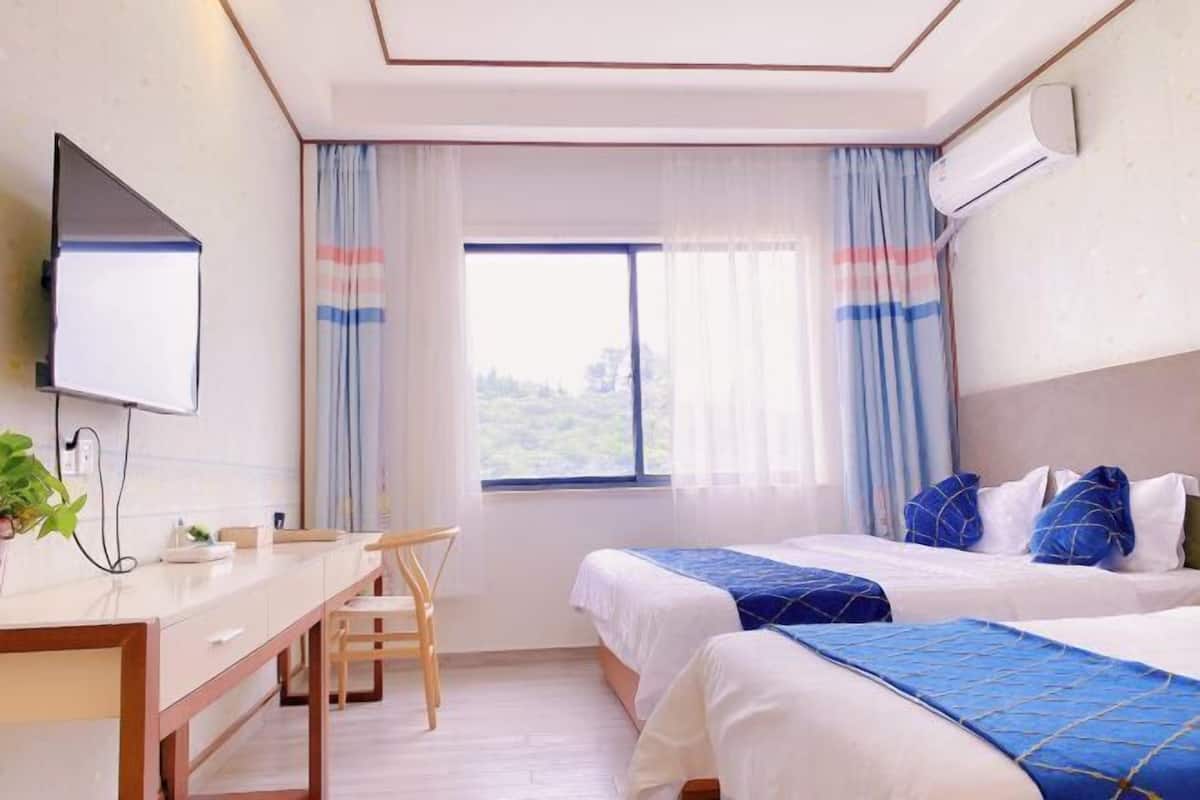 Een hotelkamer met twee bedden, een bureau, een stoel, een televisie en een raam met gordijnen.