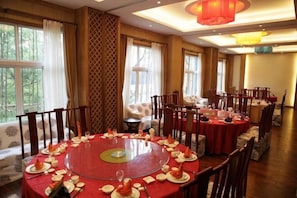 A dining area with round tables, chairs, and a central table with a red tablecloth.