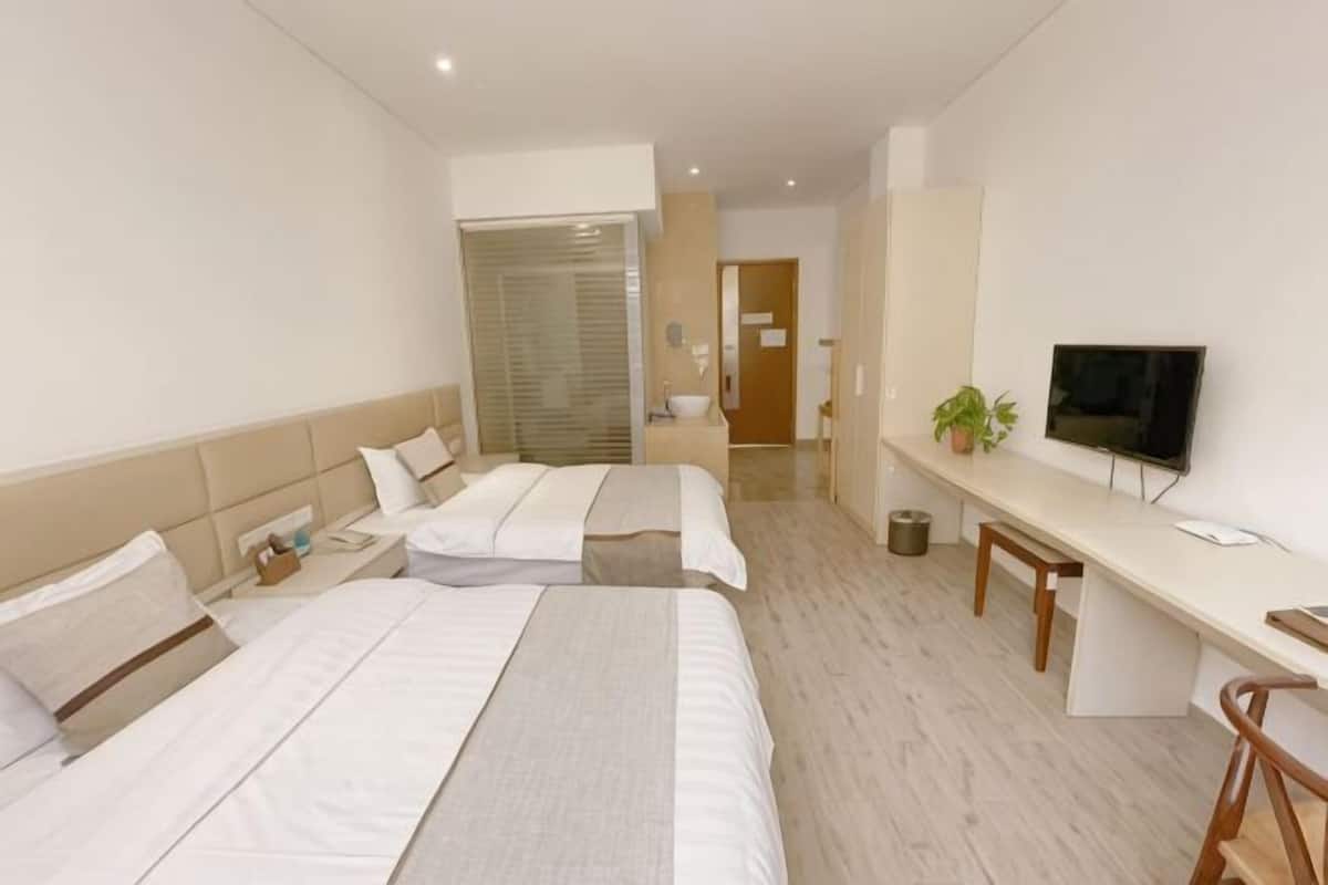 Een hotelkamer met twee bedden, een bureau, een televisie en een plant.