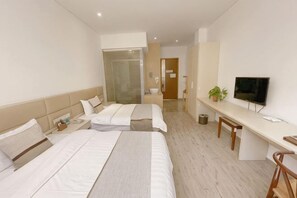 Een hotelkamer met twee bedden, een bureau, een televisie en een plant.