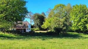A house with a balcony, surrounded by a grassy field and trees. - Quiet house in the Black Mountain (Les Martys)