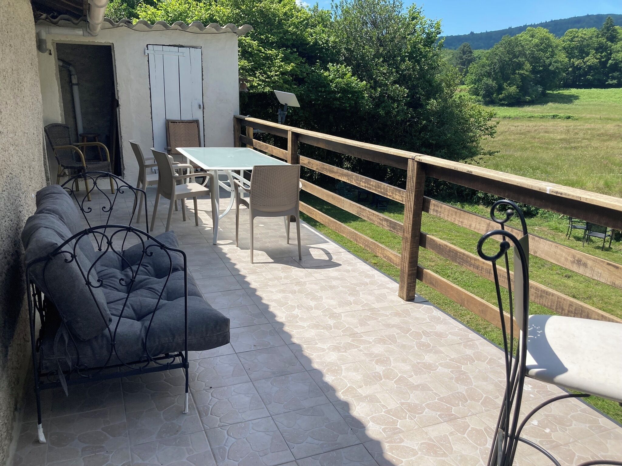 A patio with a sofa, chairs, and a table, overlooking a green landscape.
