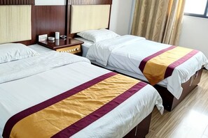 A hotel room with two beds, a nightstand, and a window with curtains.