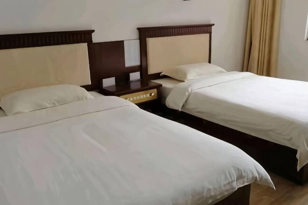 A hotel room with two beds, each with a wooden headboard and white bedding.