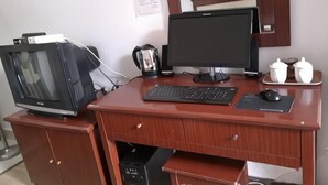 Un bureau en bois avec un écran d’ordinateur, un clavier, une souris et un téléviseur.