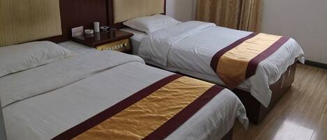 Two beds with headboards, a nightstand, and a window with curtains.