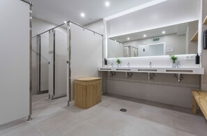 A modern bathroom with a large mirror, three sinks, a shower area, and a trash bin. - Urban Cube Hostel Sevilla (Seville)