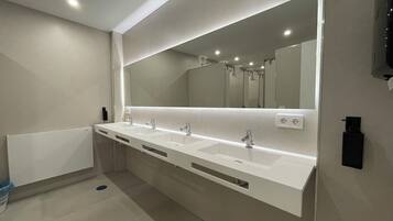 A modern bathroom with three sinks, a large mirror, and a towel rack.