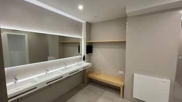 Een moderne badkamer met een lange wastafel, een grote spiegel en een bankje.