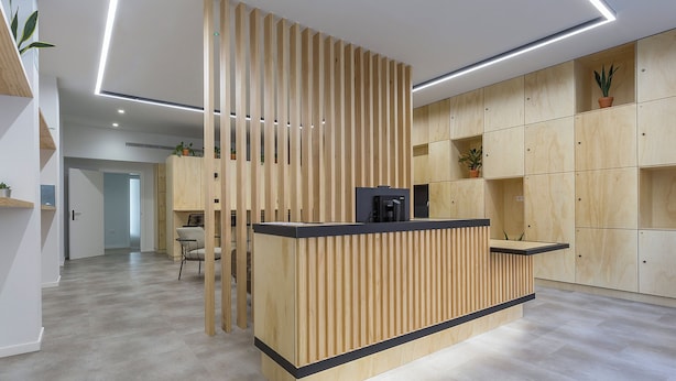 A modern reception desk with vertical slats, a coffee machine, and a potted plant. - Urban Cube Hostel Sevilla (Seville)