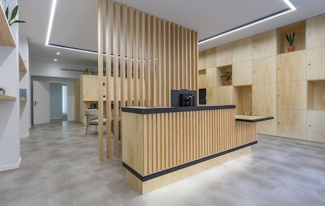 A modern reception desk with vertical slats, a coffee machine, and a potted plant.