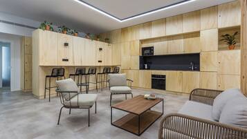 Una cocina moderna con electrodomésticos integrados, armarios de madera y un rincón de estar con sillas y sofá.