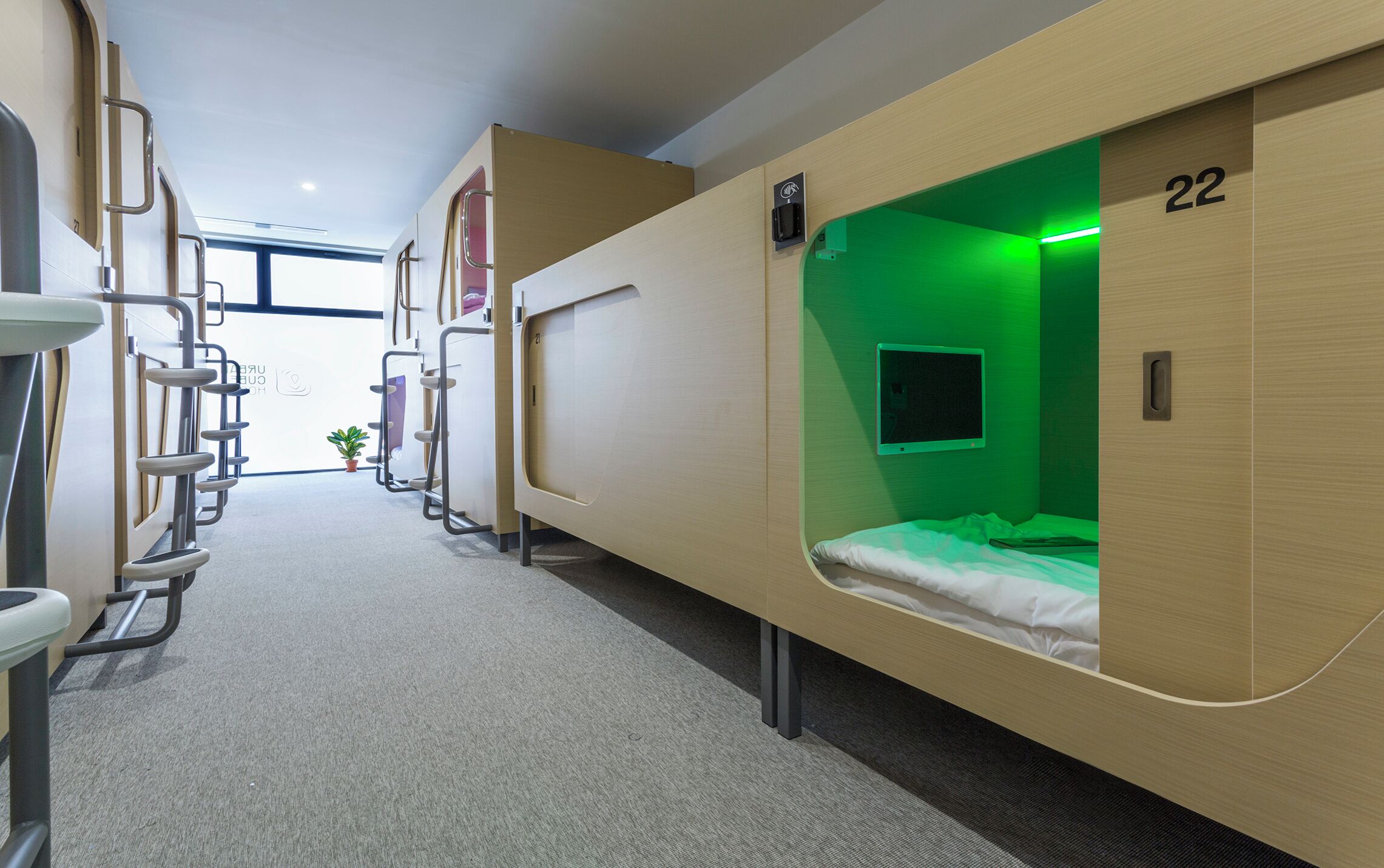 A hotel room with bunk beds, a small window, and a green-lit reading light.
