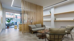 A modern interior with a sofa, two armchairs, a coffee table, and a wooden partition. - Urban Cube Hostel Sevilla (Seville)